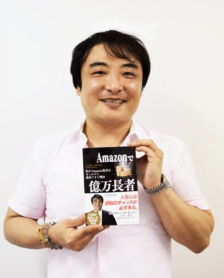 著者・坂本好隆さんが自著を持ってほほえんでいる